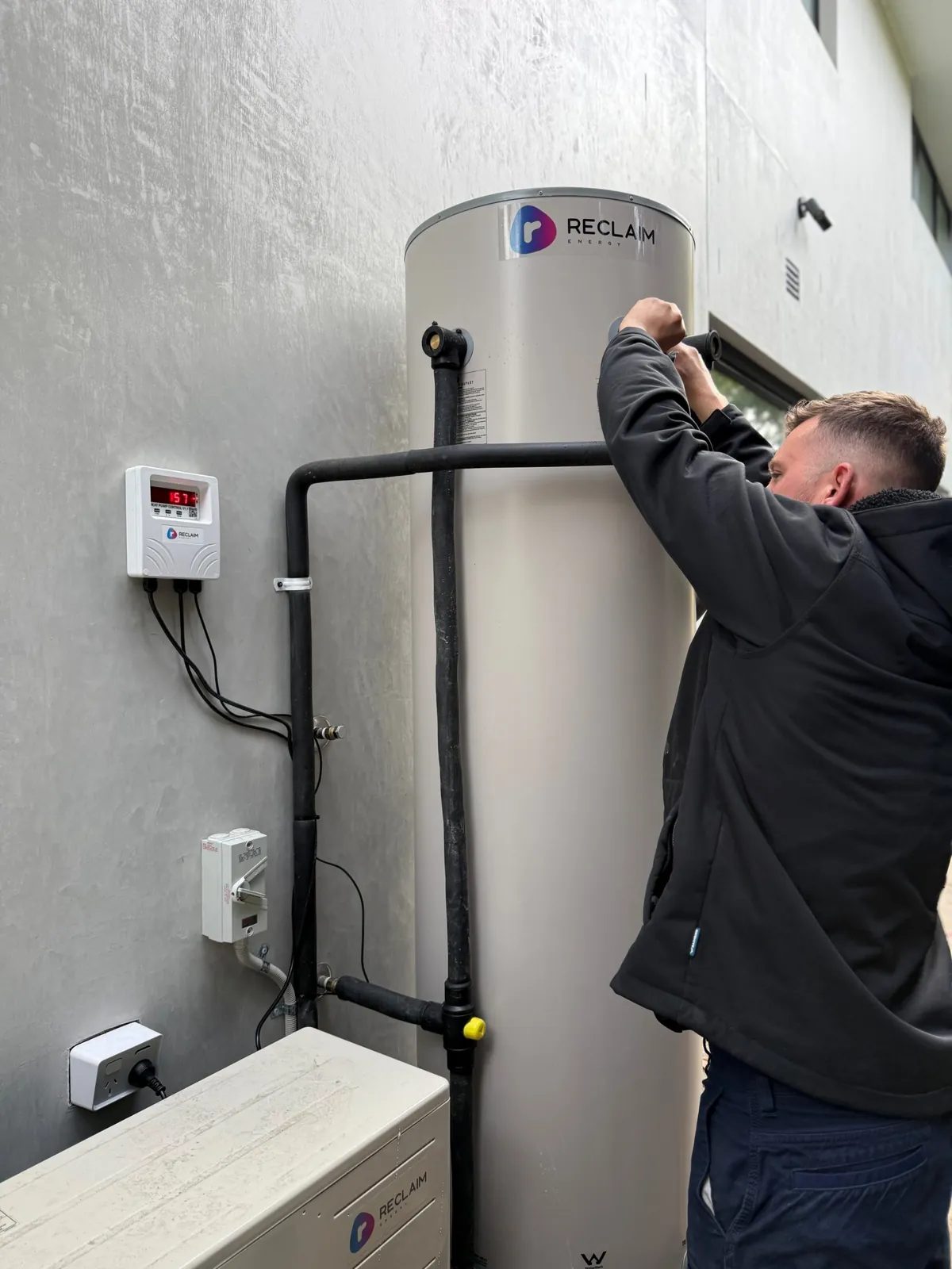 Plumber connecting a heat pump hot water system at a home